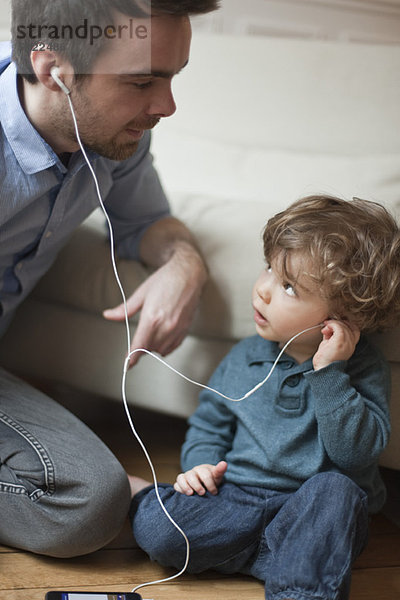 Vater und Kleinkind Sohn hören MP3-Player mit Kopfhörer  Portrait