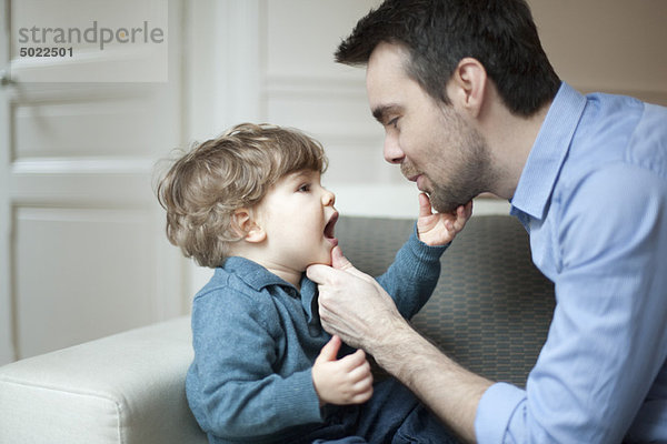 Vater untersucht die Zähne des kleinen Sohnes  Porträt