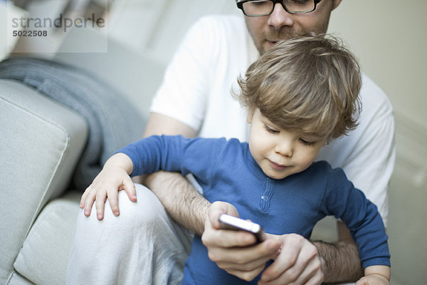Kleinkind Junge beobachtet Vater mit dem Handy