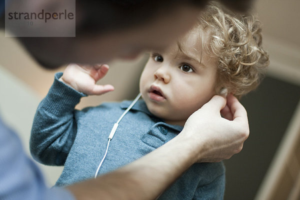 Vater hilft Kleinkind Sohn benutzen Kopfhörer