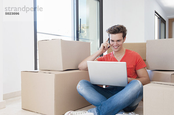 Mann mit Laptop im neuen Zuhause