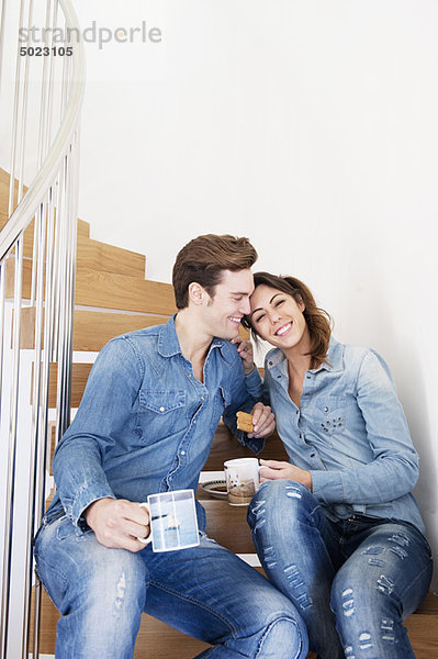 Paar trinkt Kaffee auf der Treppe
