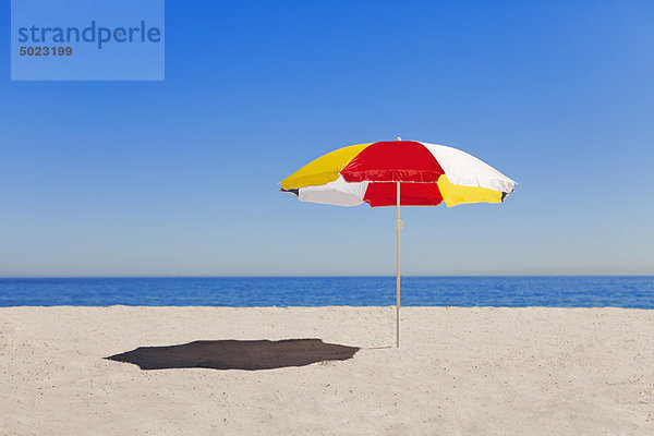 Regenschirm im Sand am leeren Strand