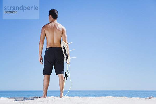 Mann mit Surfbrett am Strand