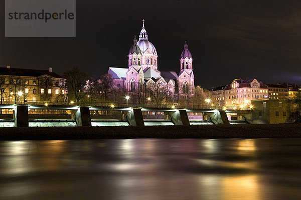 Beleuchtete Kirche und Brücke am Fluss bei Nacht