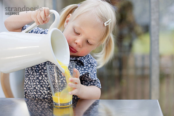 Kleinkind Mädchen schüttet ein Glas Saft aus