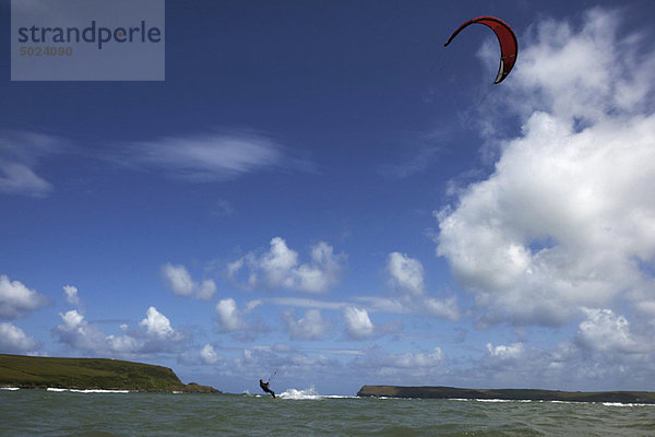 Kitesurfer auf dem Wasser unter blauem Himmel