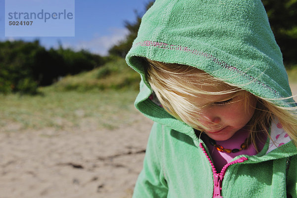 Mädchen mit Pullover am windigen Strand