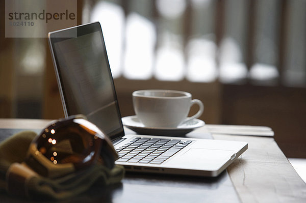 Skibrille und Laptop mit Kaffeetasse