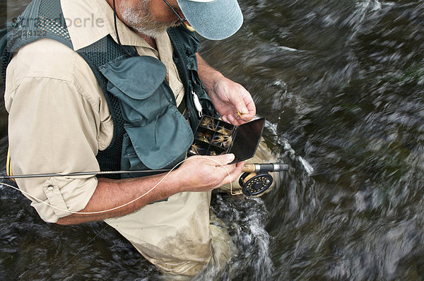 Fliegenfischer mit Fliegenbox im Fluss