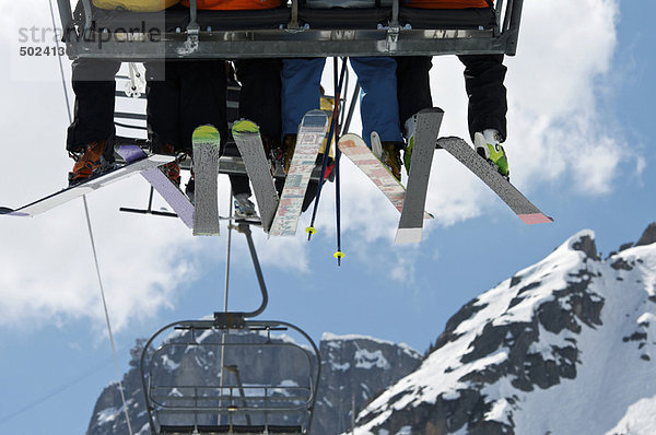 Skifahrer fahren Sessellift über die Berge