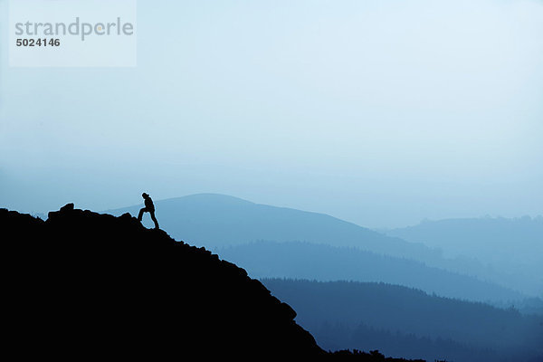 Mann beim Wandern auf felsigen Hängen