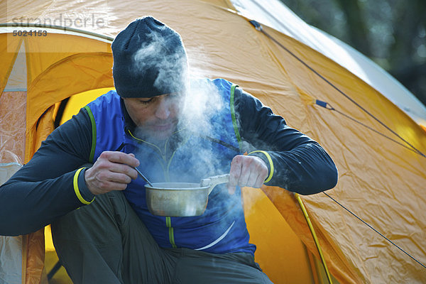 Mann kocht Essen im Campingzelt