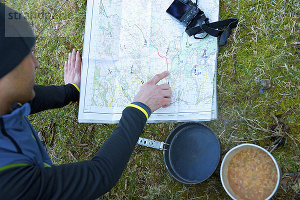 Mann untersucht Wanderkarte beim Zelten