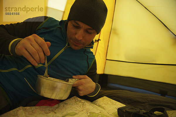 Mann beim Essen im Campingzelt