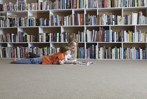 Kinder beim gemeinsamen Lesen im Bücherregal