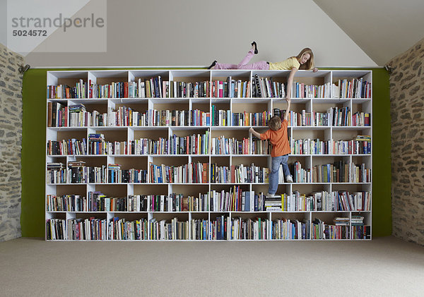 Kinder klettern im Bücherregal