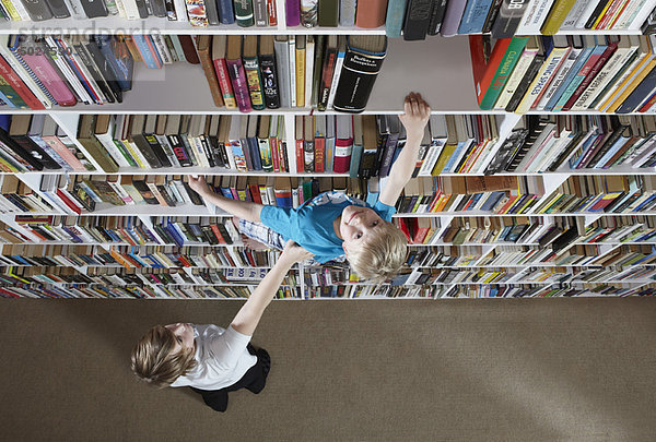 Mädchen hilft Junge klettern Bücherregale