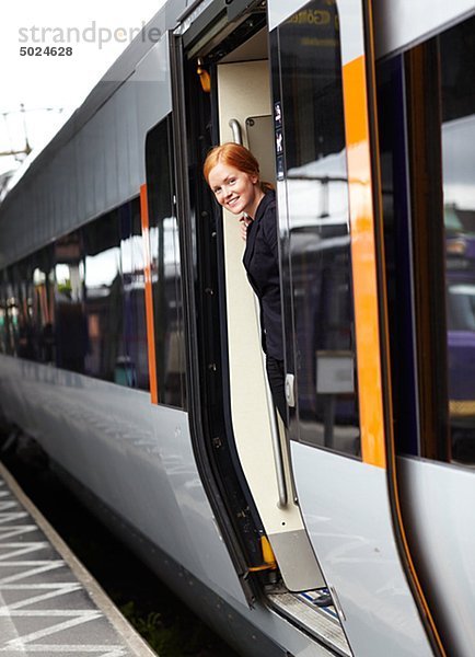 Portrait of happy young Woman in Züge Tür stehen