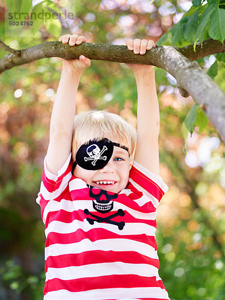 Boy von Zweig des Baumes hängen Augenklappe tragen