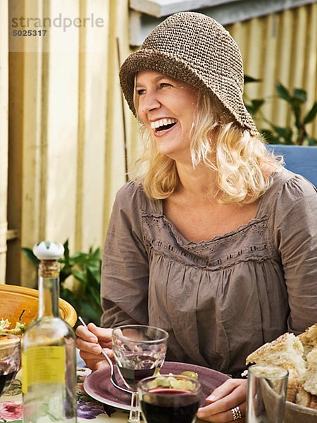 Frau sitzt auf gedeckter Tisch  lächelnd