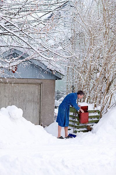 Mann im Bademantel überprüfen Mail im verschneiten Hof