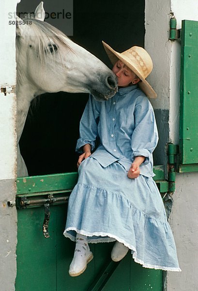 Mädchen küssen Pferde im Stall