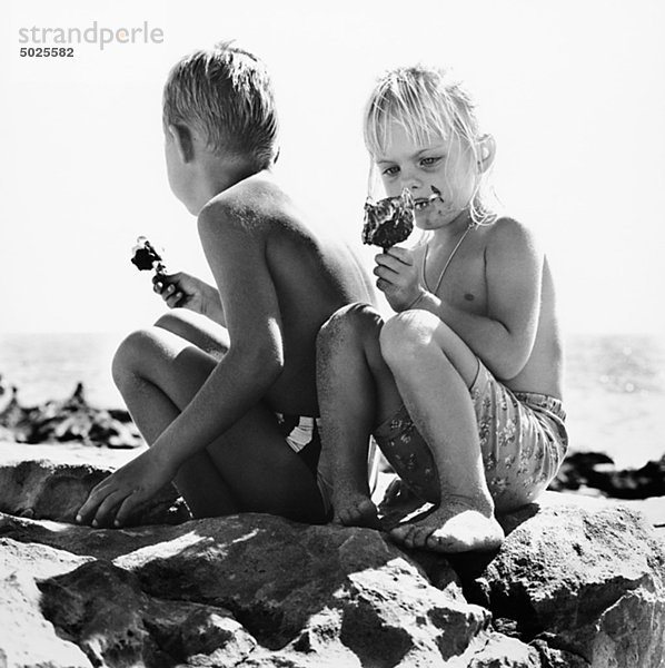 Jungen und Mädchen am Strand Eis essen