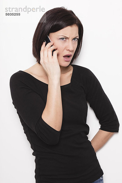 Mittlere erwachsene Frau im Gespräch auf dem Handy vor weißem Hintergrund