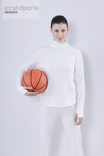 Mittlere erwachsene Frau mit Basketball auf weißem Hintergrund  lächelnd  Portrait