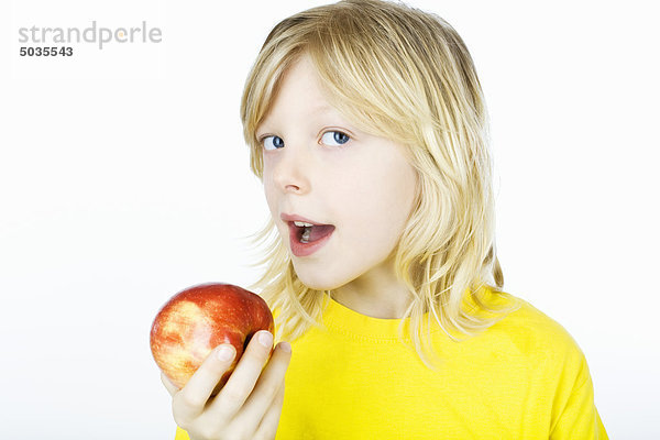 Junge hält Apfel vor den Mund  Portrait