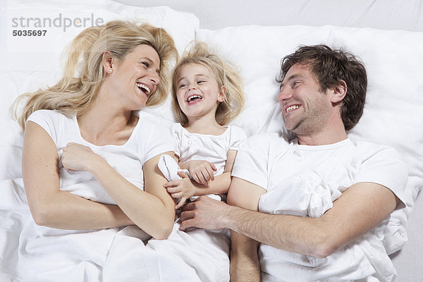 Deutschland  Bayern  München  Familie im Bett liegend  lachend