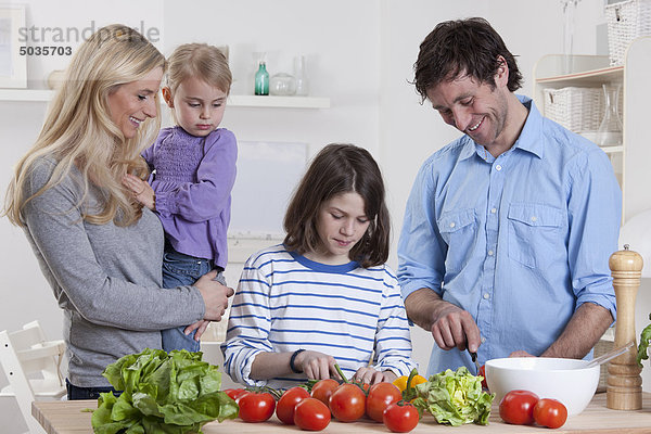 Deutschland  Bayern  München  Sohn bereitet Salat mit Vater  Mutter und Tochter neben ihnen zu.