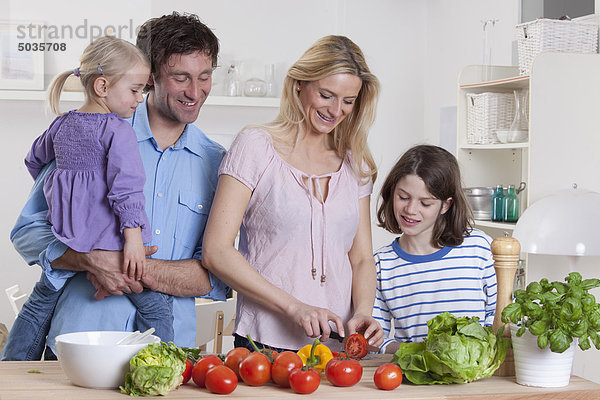 Deutschland  Bayern  München  Mutter bereitet Salat mit Sohn  Vater und Tochter neben ihnen zu.