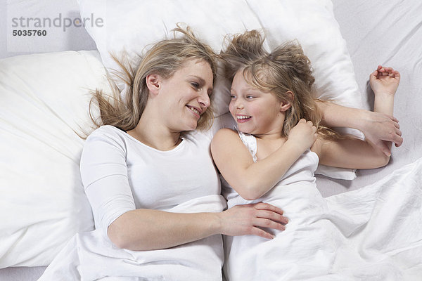 Deutschland  Bayern  München  Mutter und Tochter auf dem Bett liegend