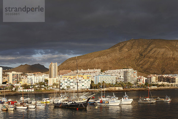 Spanien  Kanarische Inseln  Teneriffa  Los Cristianos  Blick auf Boote im Wasser mit Gebäuden und Bergen im Hintergrund