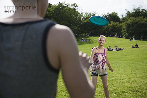 Teenager Mädchen und Junge spielen Frisbee im Park