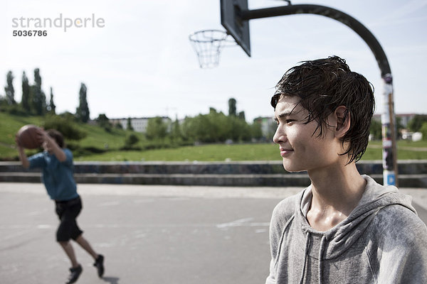 Teenager-Junge schaut weg mit dem Jungen  der im Hintergrund spielt.