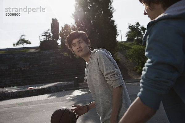 Jugendliche spielen Basketball auf dem Spielplatz.