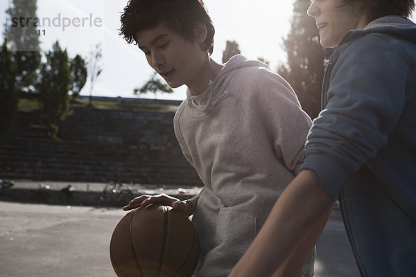 Jugendliche spielen Basketball auf dem Spielplatz.