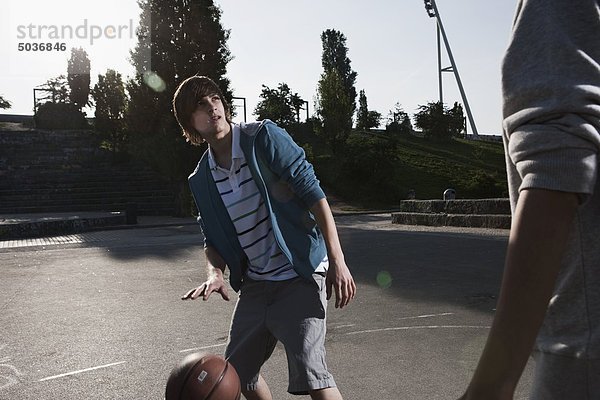 Jugendliche spielen Basketball auf dem Spielplatz.