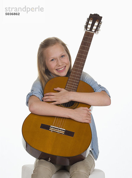 Mädchen umarmt Gitarre vor weißem Hintergrund  lächelnd  Portrait
