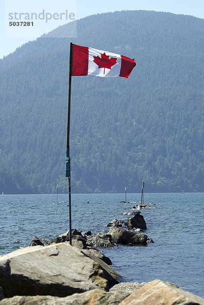 Kanadische Flagge am Fahnenmast Bandware auf Felsen in Harrison Lake  b.c.  Kanada senden