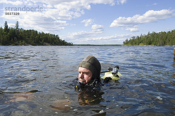 Mann in Tauchausrüstung floating bei der Oberfläche eines Sees
