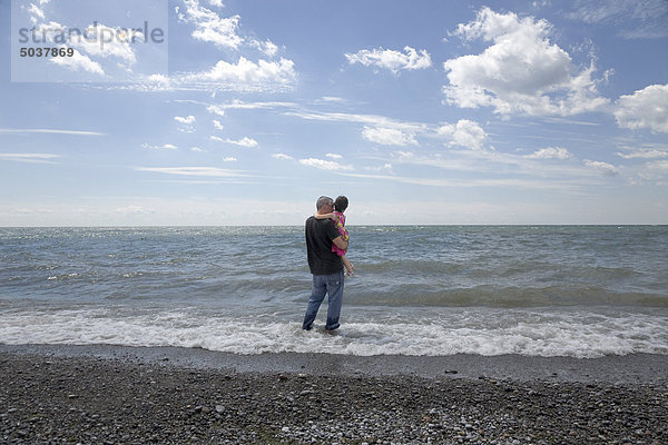 Vater seiner Tochter hält und stehen in der Brandung am Seeufer  Ontario  Kanada