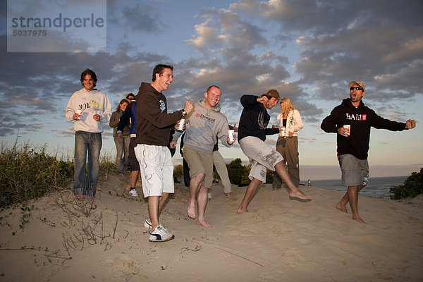 Reisende feiern gegen einen schönen Sonnenuntergang über den Strand  Jeffreys Bay  Südafrika