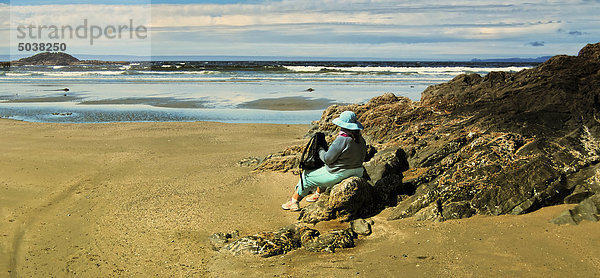 Frau sitzt am Strand mit Blick auf Meer  Vancouver Island  b.c.  Kanada