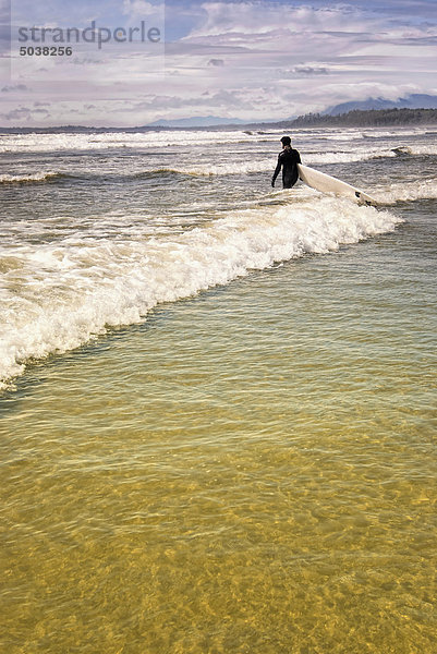 Surfer standing in the surf  Long Beach  Vancouver Island  B.C.  Canada