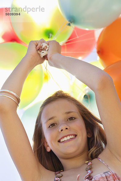 Porträt eines Mädchens  das mit Luftballons spielt und lächelt