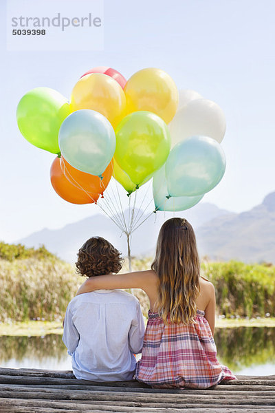 Rückansicht von Geschwistern beim Ballonspiel am Pier